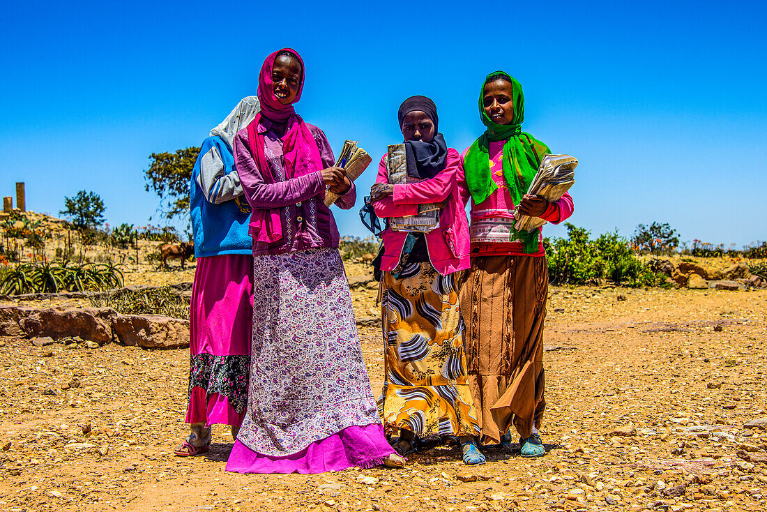 Bunt gekleidete Schulmädchen auf dem Heimweg in der prä-aksumitischen Siedlung von Qohaito (Koloe), Eritrea, Afrika