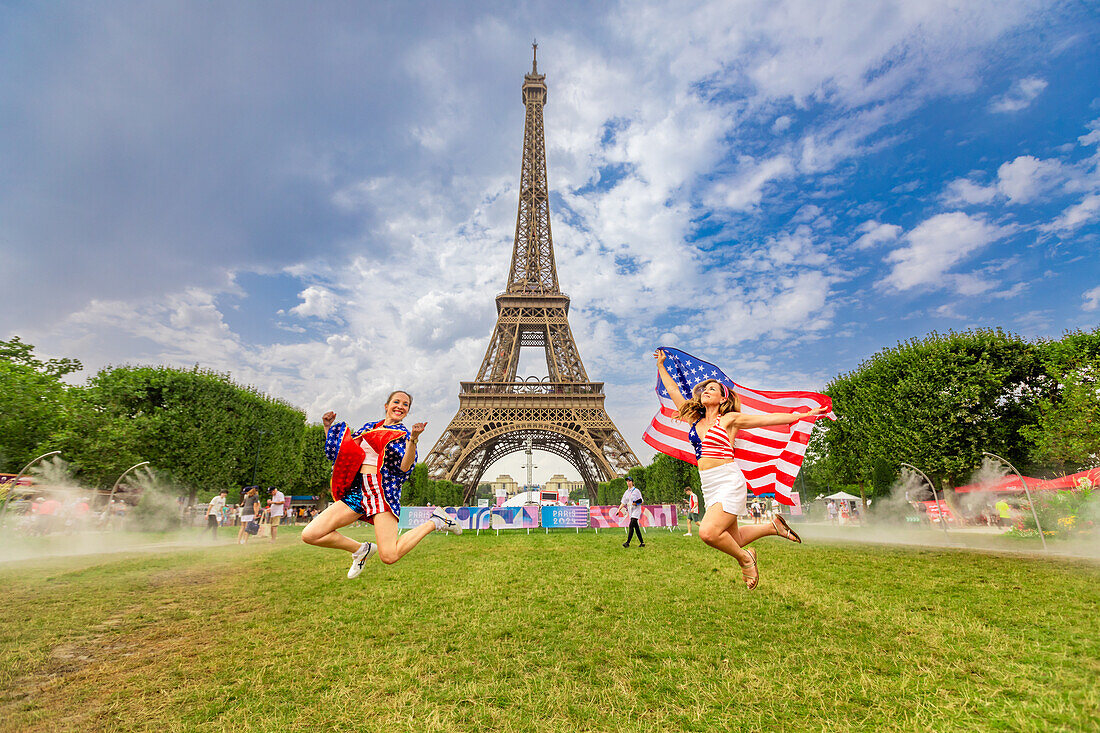 Patriotic American Woman jumping and cheering for Team USA and the Paris 2024 Olympics in front of the Eiffel Tower, Paris, France, Europe