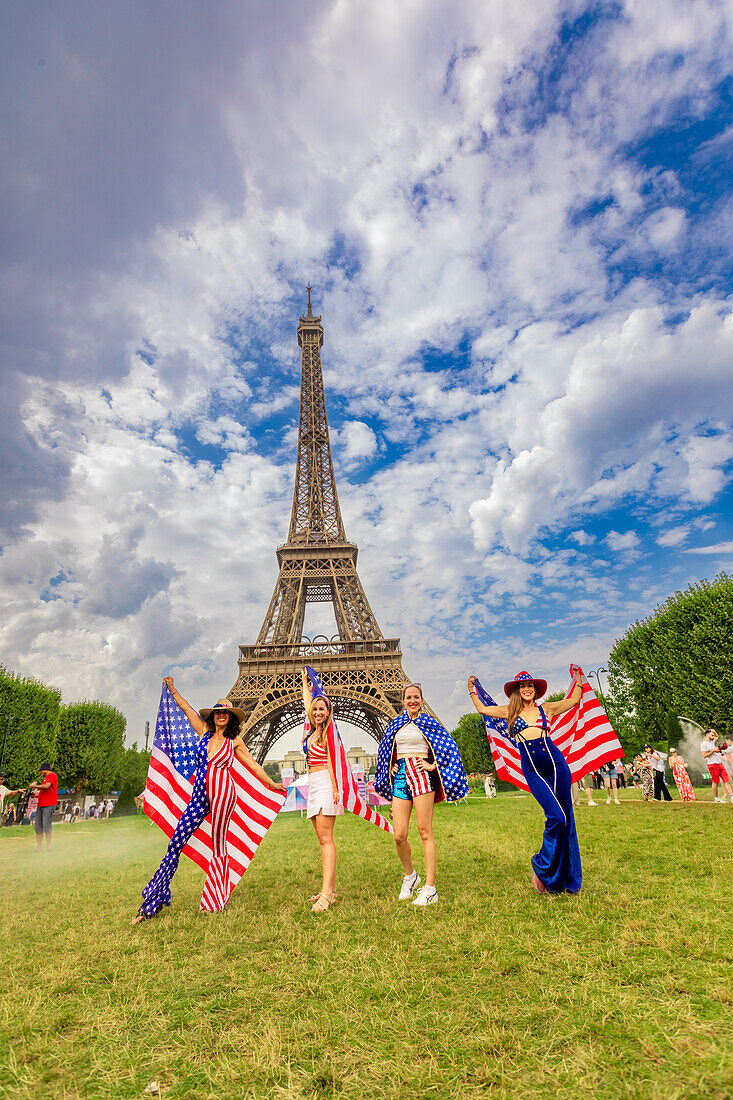 Patriotische amerikanische Frau springt und jubelt für das Team USA und die Olympischen Spiele Paris 2024 vor dem Eiffelturm, Paris, Frankreich, Europa