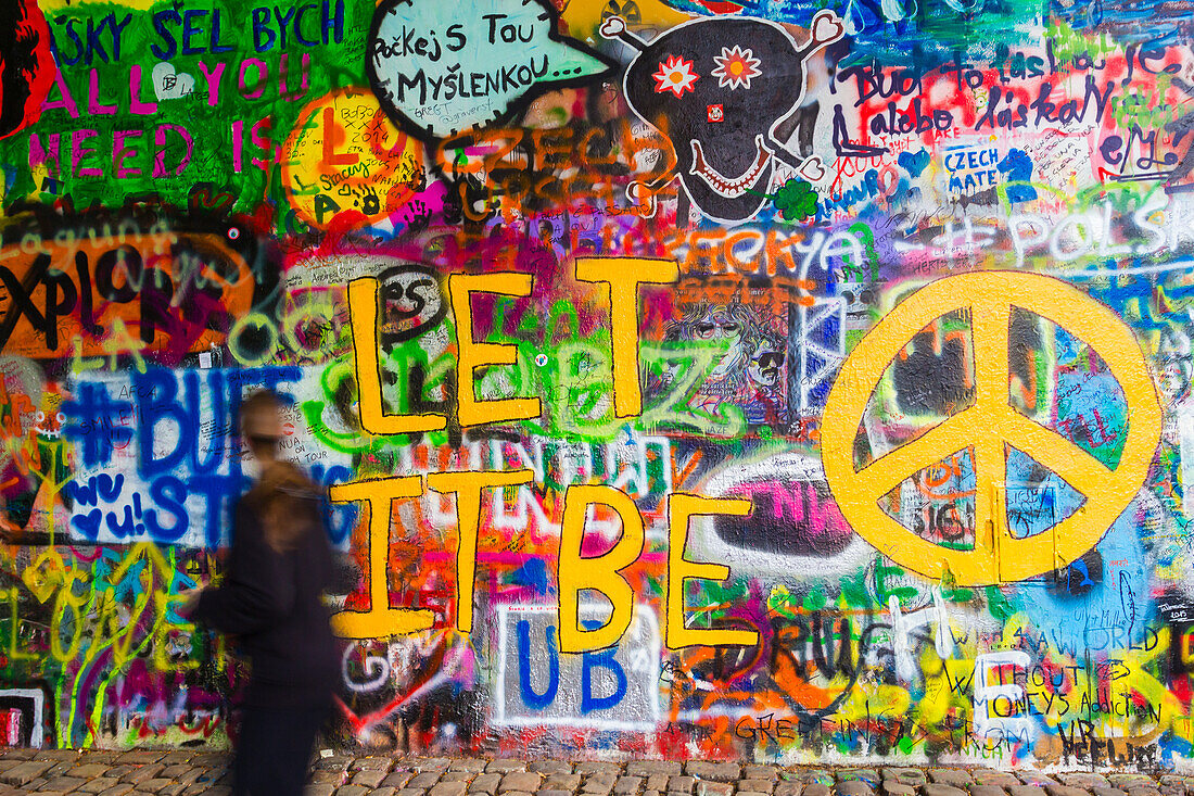 A woman passing by the colourful John Lennon Wall, Lesser Town, Prague (Czechia), Europe