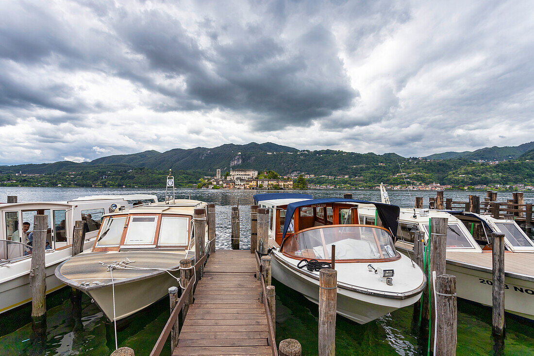 Boote im kleinen Hafen von Orta, mit der Insel San Giulio im Hintergrund, Orta, Bezirk Novara, Italienische Seen, Piemont, Italien, Europa