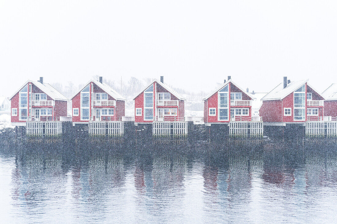 Reihe traditioneller roter Rorbu unter starkem Schneefall, Svolvaer, Austvagsoya, Lofoten-Inseln, Norwegen, Skandinavien, Europa