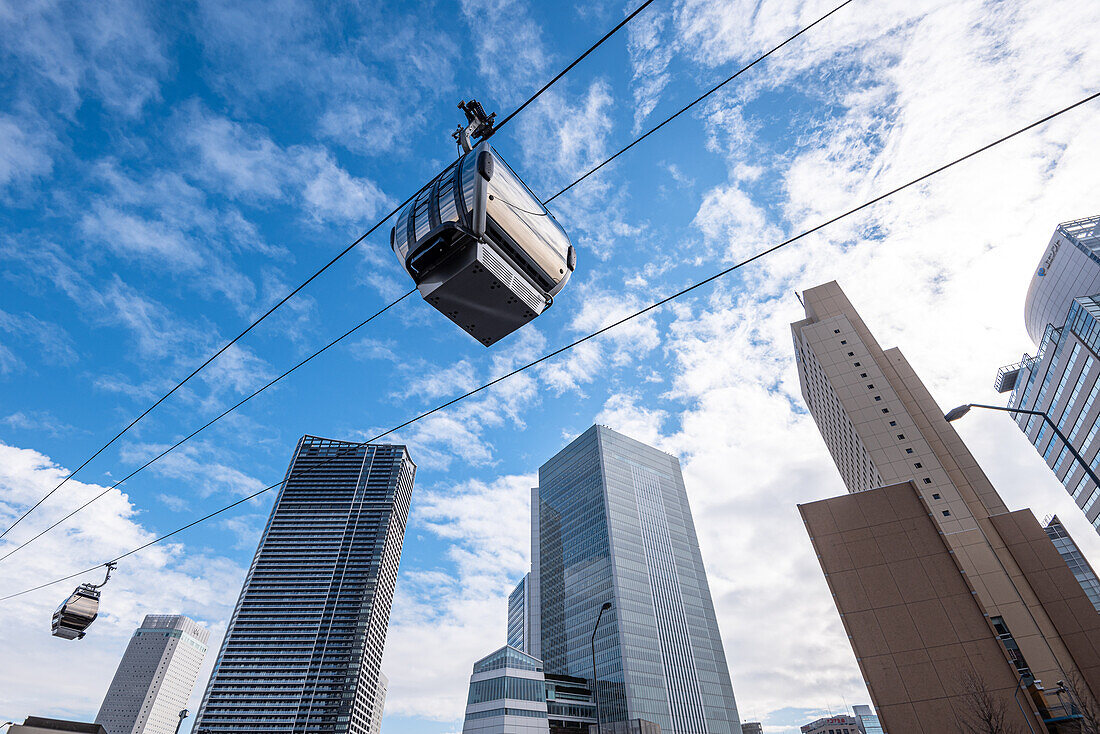 Yokohama Air Cabin (Seilbahn) vor blauem Himmel und hoch aufragenden Wolkenkratzern, Tokio, Honshu, Japan, Asien