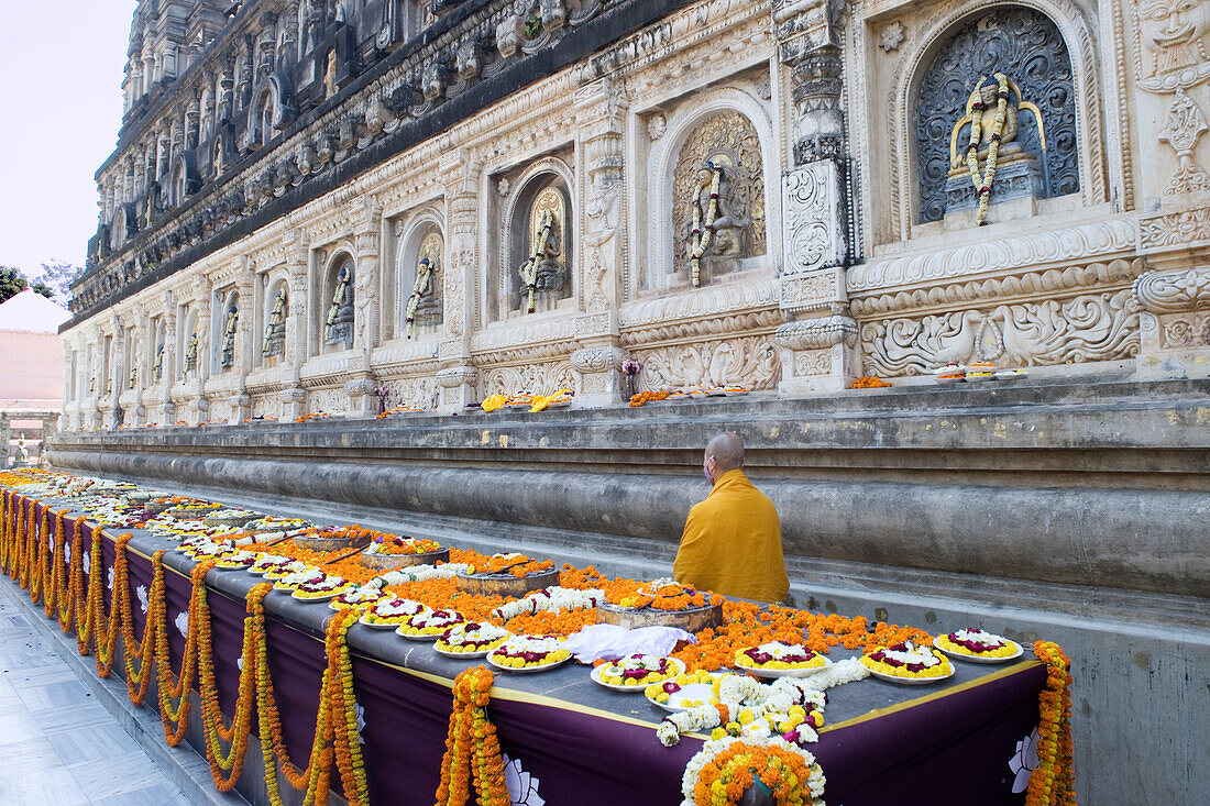 Blumenopfer und ein Mönch im buddhistischen Mahabodhi Mahabihara-Tempel (Große Stupa), Bodh Gaya, UNESCO-Weltkulturerbe, Bihar, Indien, Asien