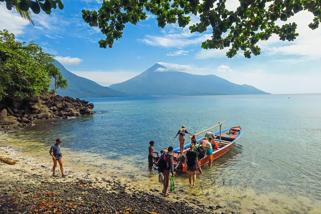 Touristen auf einer Bootsfahrt vom Kalea-Strand mit dem aktiven Vulkan Karangetang dahinter, Kalea, Siau-Insel, Sangihe-Archipel, Nordsulawesi, Indonesien, Südostasien, Asien