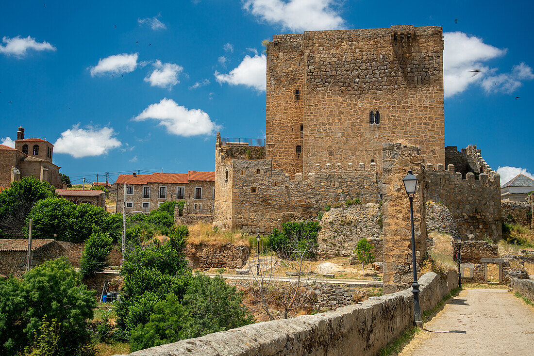 Faszinierender Blick auf die Burg Davila und die mittelalterliche Brücke über den Fluss Tormes in Puente del Congosto, Salamanca, Spanien.