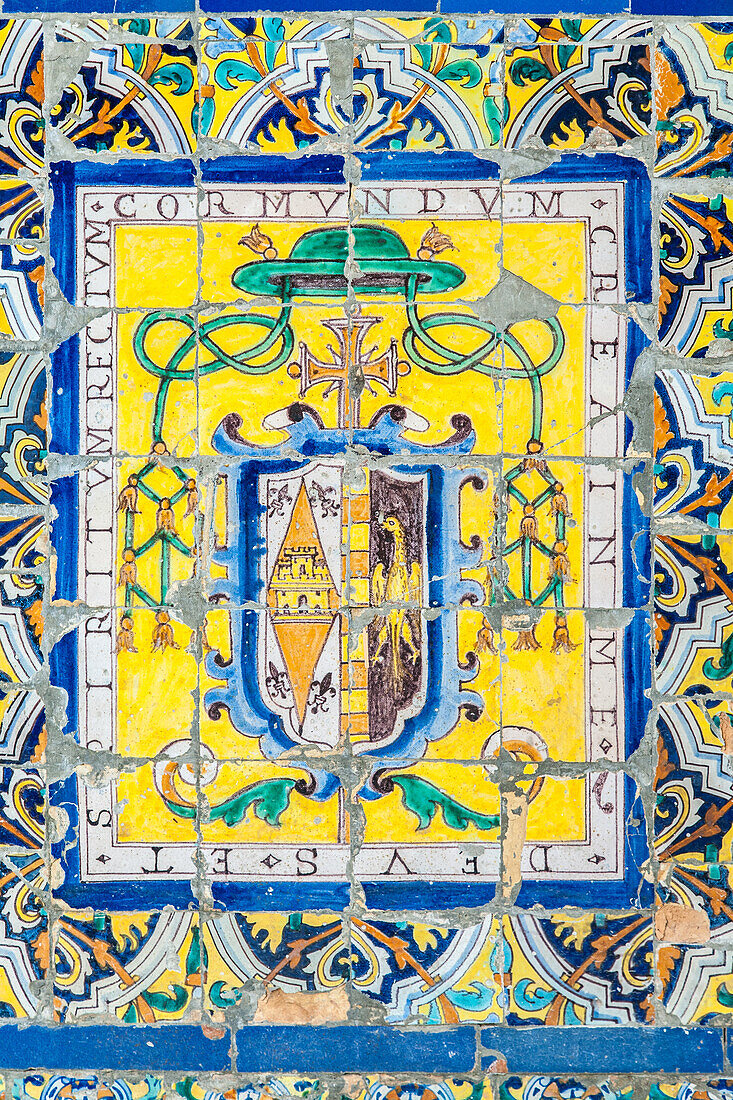 Intricately designed ecclesiastical badge on antique glazed ceramic tiles in the Fine Arts Museum in Seville, Spain.