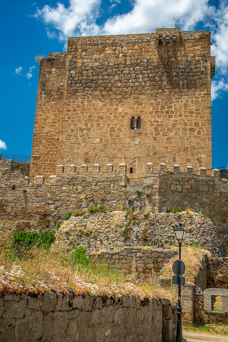 Blick auf die mittelalterliche Burg Davila in Puente del Congosto, in der Provinz Salamanca, Spanien. Die historische Architektur erhebt sich vor einem strahlend blauen Himmel.