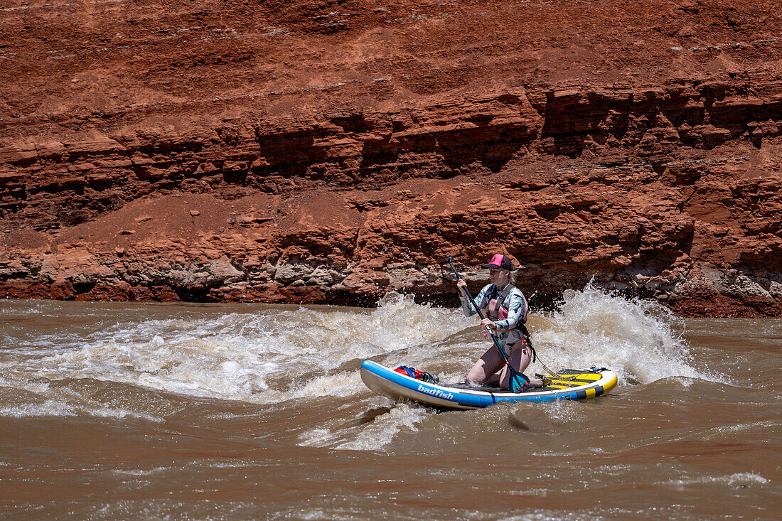 Eine junge Frau paddelt im Wildwasser des White's Rapid auf dem Colorado River bei Moab, Utah.