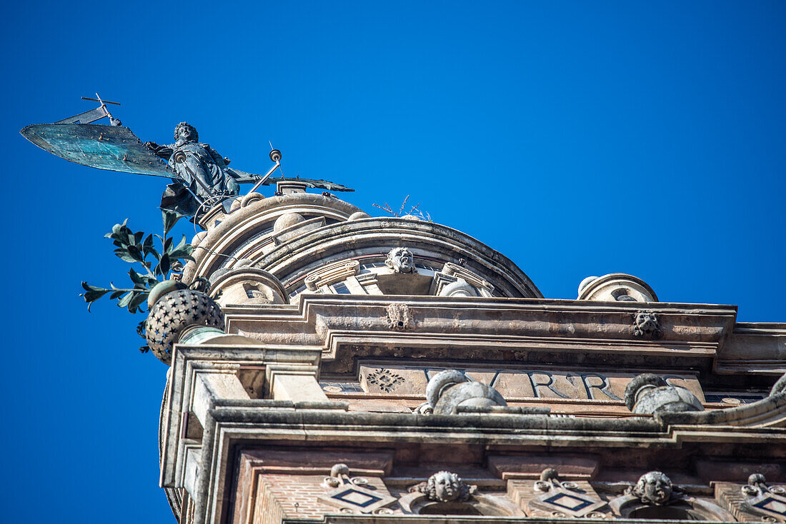 Tiefblick auf die Giraldillo-Statue auf der Spitze von La Giralda in Sevilla, Andalusien, Spanien, vor einem klaren blauen Himmel.