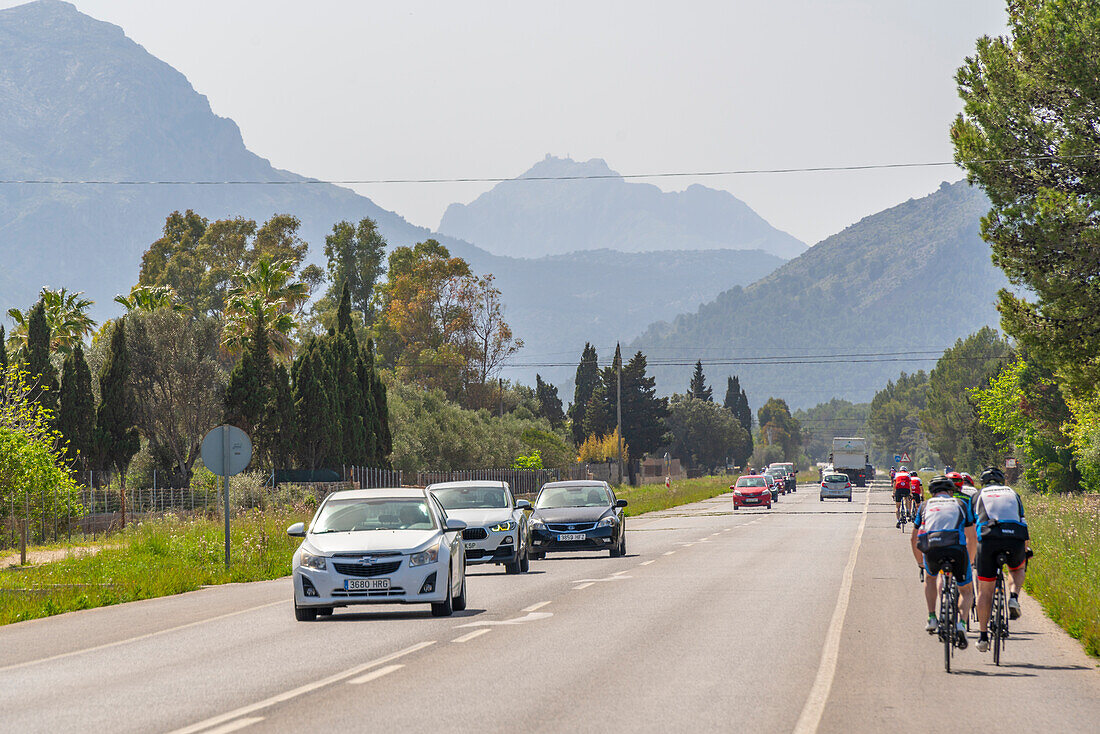 Blick auf Radfahrer und Autos auf der Straße und in den Hügeln von Polllenca, Mallorca, Balearen, Spanien, Mittelmeer, Europa