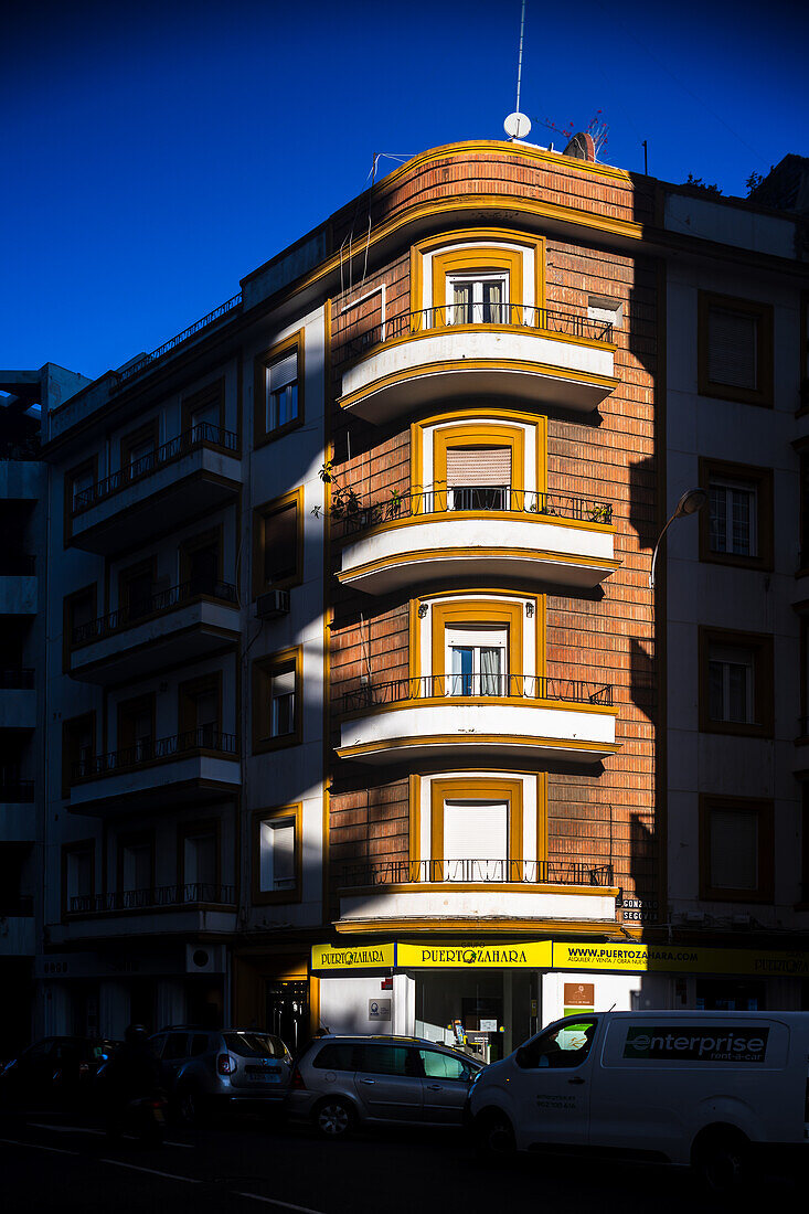 Architectural shot of a residential building in the vibrant Los Remedios district of Seville, Spain, capturing the building's unique design and color in natural light.