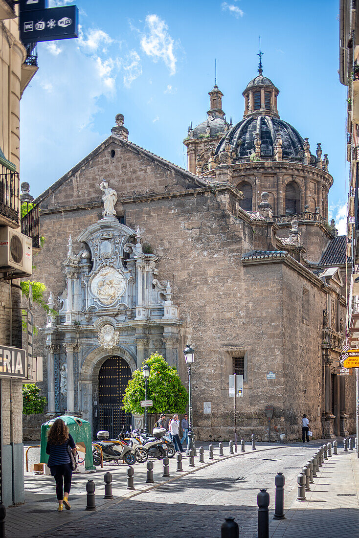 Stunning view of the historic Church of Santos Justo y Pastor in Granada, Spain. Captures the intricate architecture and vibrant street life around this landmark.