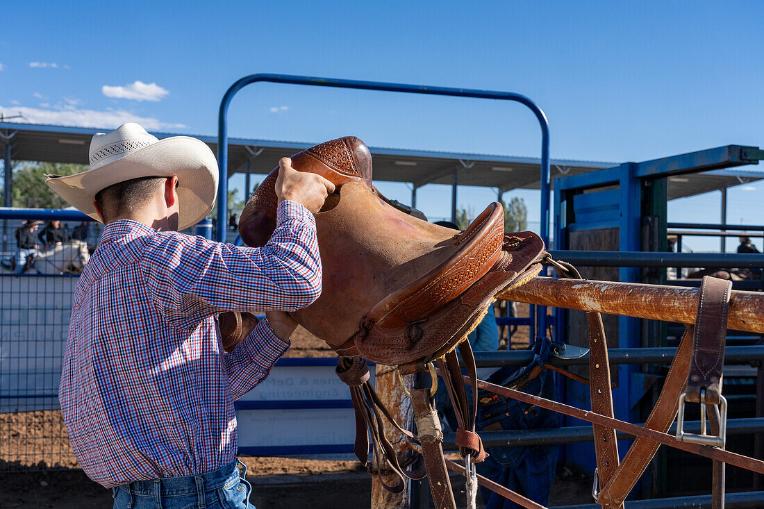 Saddle-Bronc-Cowboy Taggyrt Moses hebt seinen Sattel auf, bevor er an einem Rodeo im ländlichen Utah teilnimmt. Man beachte das Fehlen eines Sattelhorns.