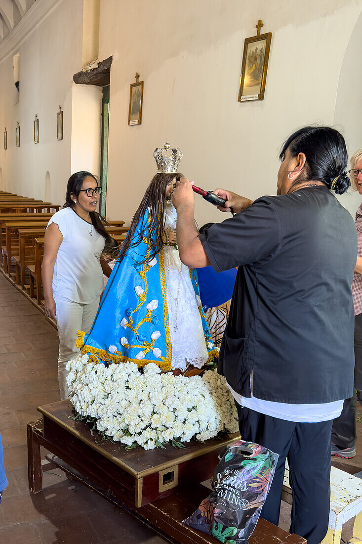 Gemeindemitglieder bereiten religiöse Statuen und Ikonen in der Kirche für die Prozession am Tag des Heiligen Josef in Cachi, Argentinien, vor. Diese Frau benutzt einen Lockenstab, um das Haar der Jungfrau Maria zu kräuseln.