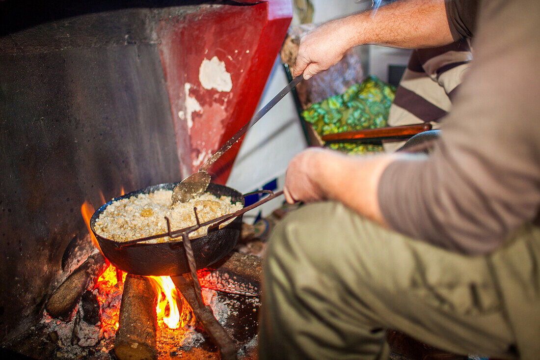 Eine Person kocht Migas auf traditionelle Art über einem offenen Feuer in Villaviciosa de Córdoba, Andalusien, Spanien.