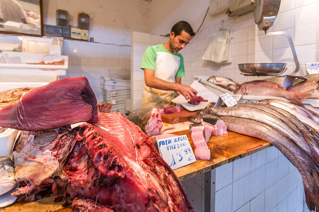 Fischhändler schneidet frischen Fisch auf dem Mercado de Abastos in Sanlucar de Barrameda, Cadiz, Andalusien, Spanien. Traditionelle Marktszene mit frischen Meeresfrüchten.