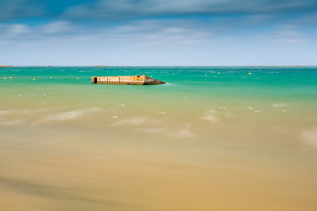 Tranquil long exposure shot of the Mulberry B remains on Gold Beach, Arromanches, Normandy, France. Captures the serene atmosphere and historical significance.