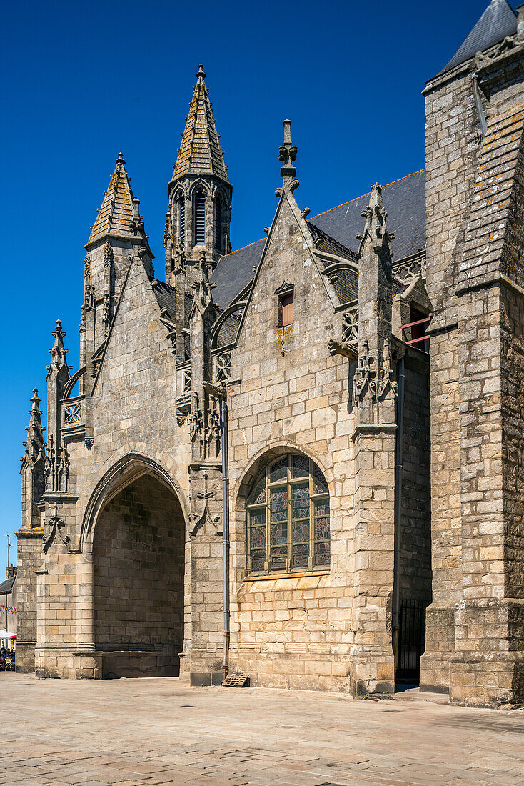 Blick auf das historische Collegiale Saint Aubin in Guerande, Frankreich, mit seiner schönen Steinarchitektur und den komplizierten Details vor einem klaren blauen Himmel.