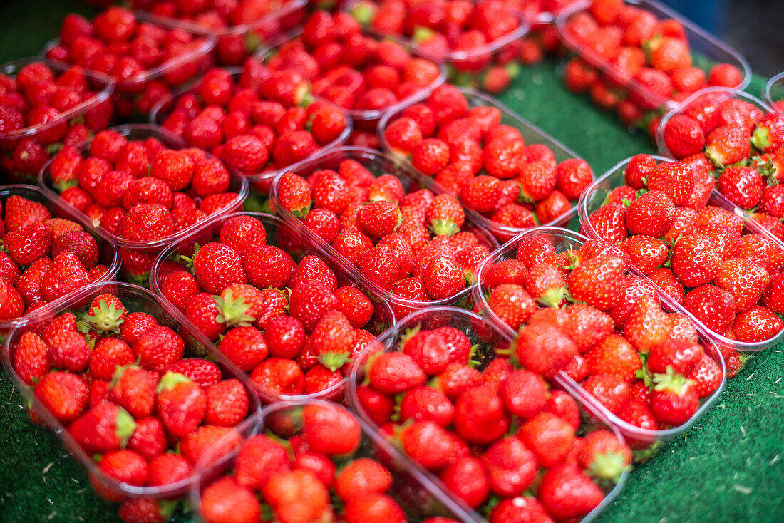 Fresh strawberries in plastic containers on display at a market in Vannes, Brittany, France. A vibrant and appetizing scene.