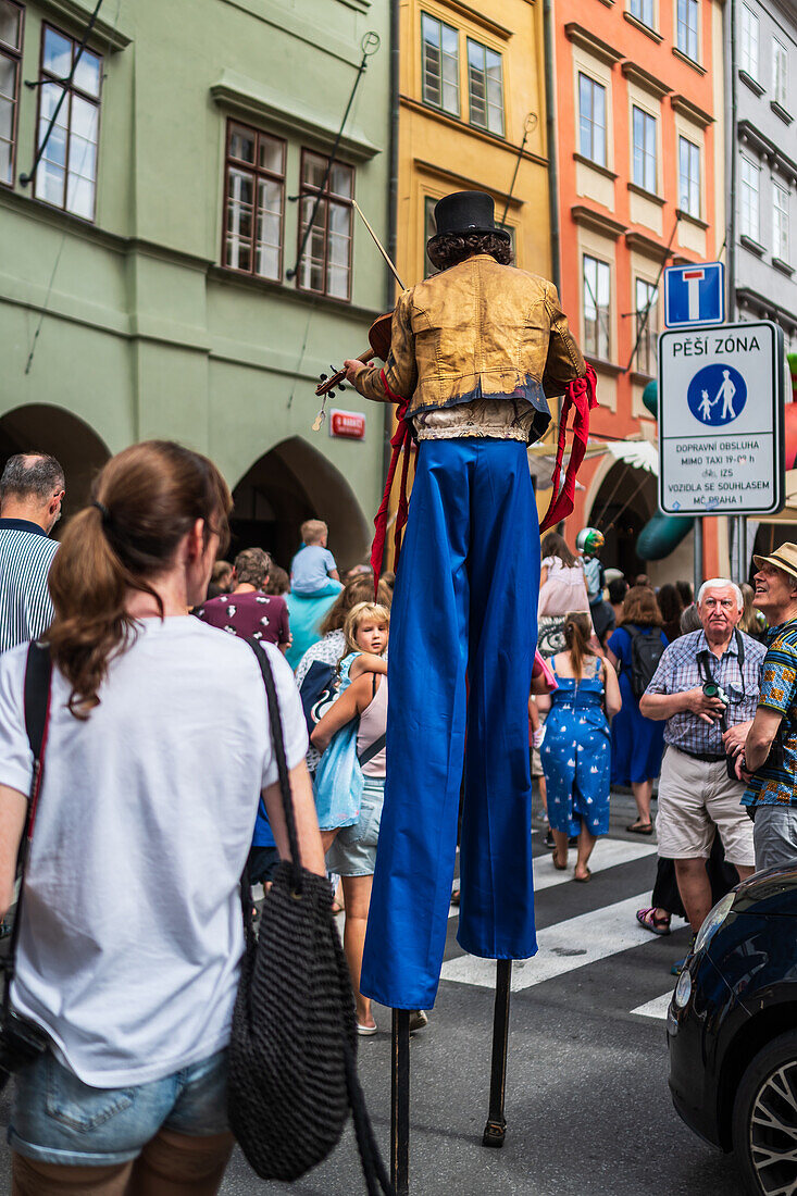 Künstler spielt Geige, während er auf Stelzen bei der Puppenparade vom Marienplatz zum Altstädter Ring läuft, während des Prager Straßentheaterfestivals Behind the Door, Prag, Tschechische Republik