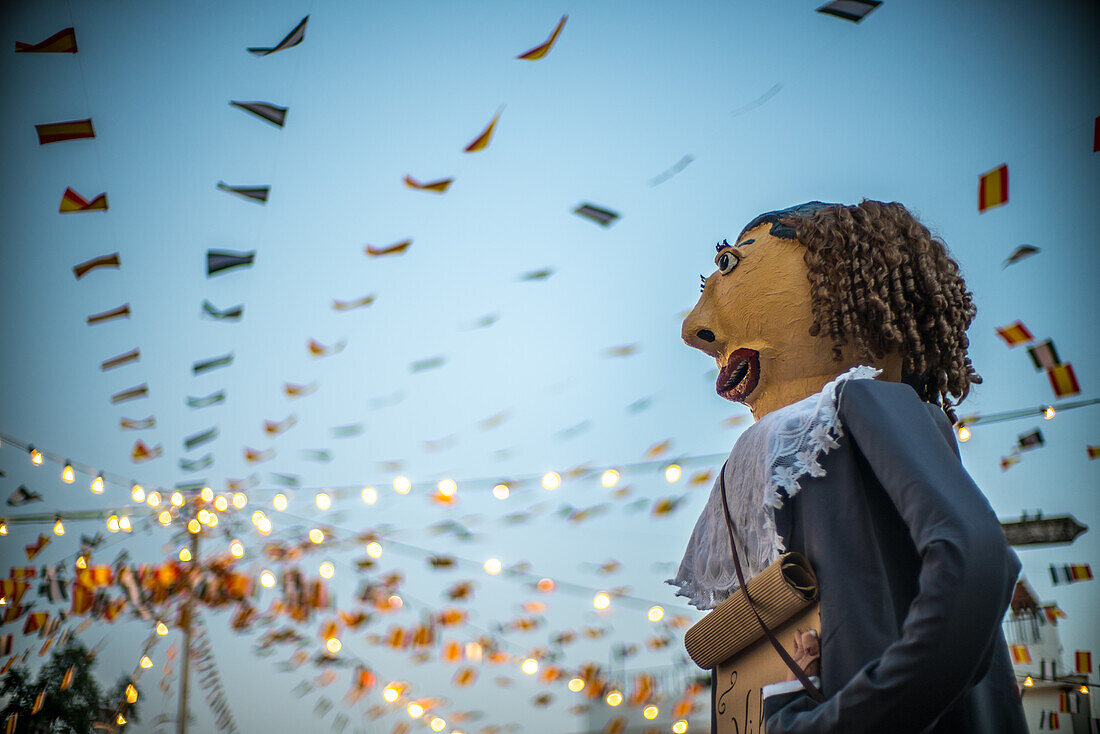 Gigantes y Cabezudos at the festival in Fuenteheridos, Huelva, Andalucia, Spain. Traditional Spanish giant puppet celebration with festive lights and decorations.