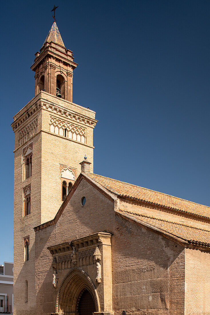 Blick auf die historische Kirche San Marcos mit ihrer gotischen Mudéjar-Architektur in Sevilla, Spanien. Der klare blaue Himmel hebt die komplizierten Details hervor.