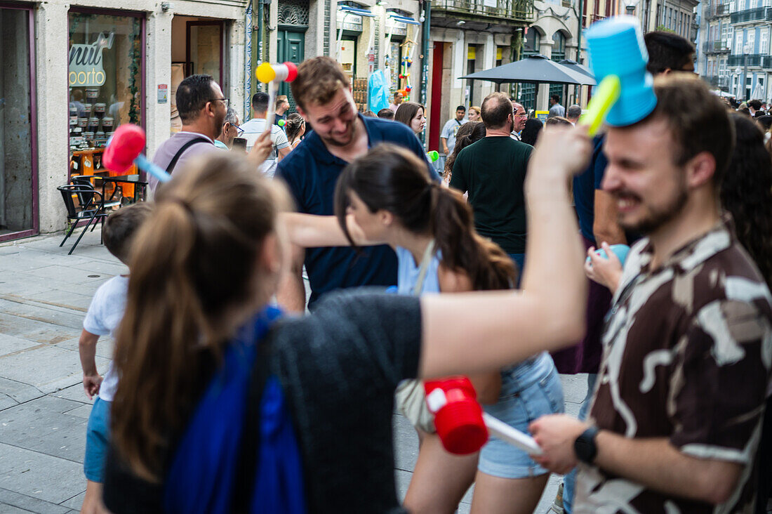 Begrüßung von Menschen mit welkem Lauch und Plastikhämmern während des Johannisfestes von Porto (Festa de Sao Joao do Porto ) in der Nacht zum 23. Juni (Johannisnacht) in der Stadt Porto, Portugal