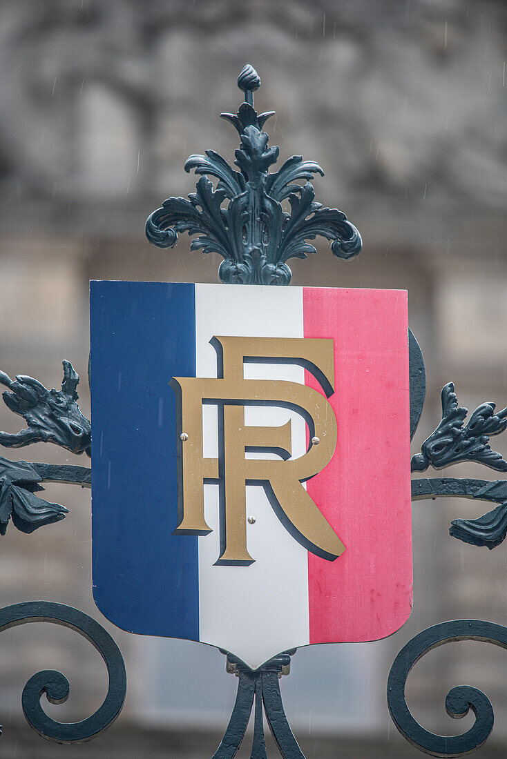 Nahaufnahme eines französischen Wappens an einem dekorativen Tor in Vannes, Bretagne, Frankreich. Das Emblem zeigt die französische Trikolore und goldene Buchstaben.