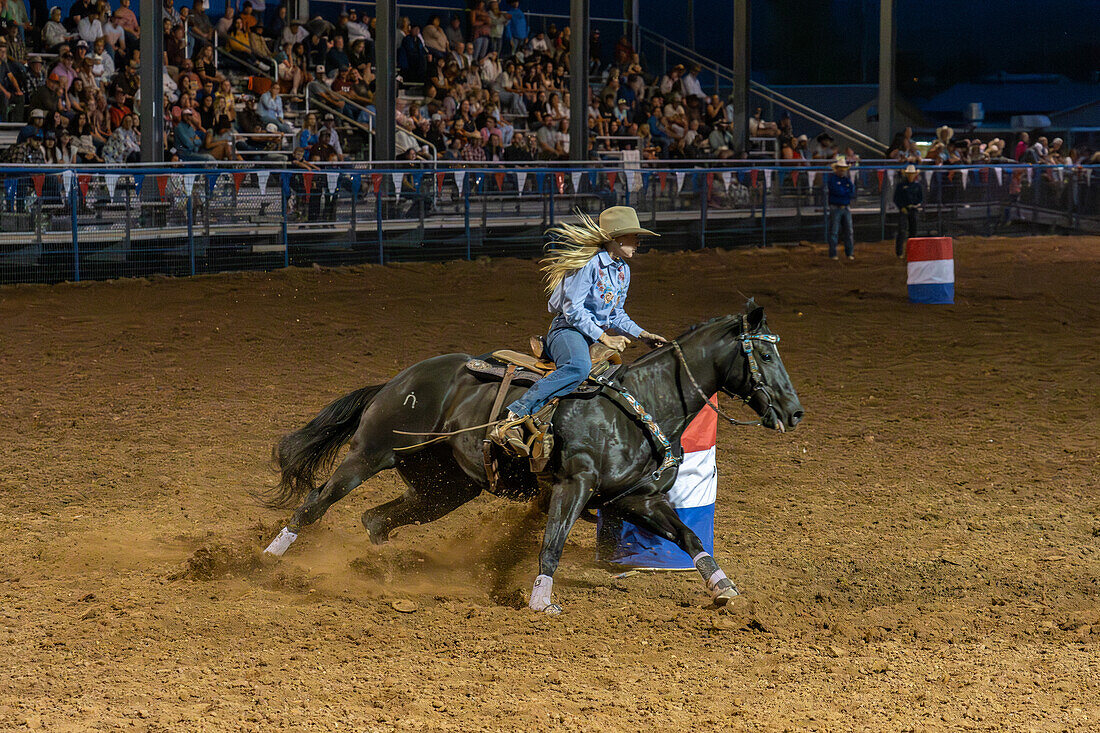 Ein Cowgirl dreht sich während eines Rodeo-Wettbewerbs im ländlichen Utah um ein Fass.