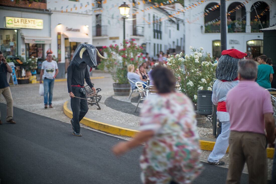 Traditionelles Gigantes y Cabezudos-Festival in Fuenteheridos, Huelva, Andalusien, mit Menschen in großen Kostümen, die durch die Straßen ziehen.