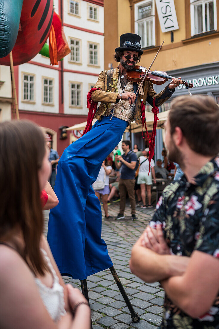 Artist plays violin while walking on stilts at the Parade of puppets from Marián Square to Old Town Square during the Prague Street Theatre Festival Behind the Door, Prague, Czech Republic