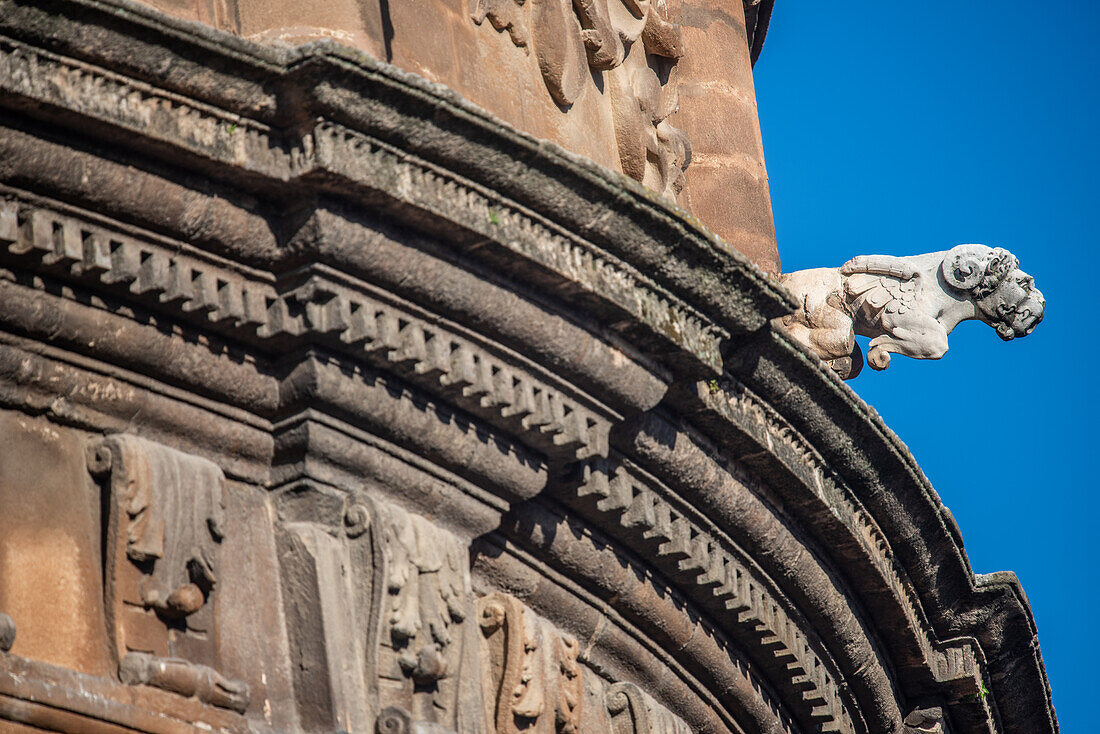 Close up of a renaissance gargoyle on the Seville Cathedral in Andalusia, Spain highlighting architectural detail against a clear blue sky.