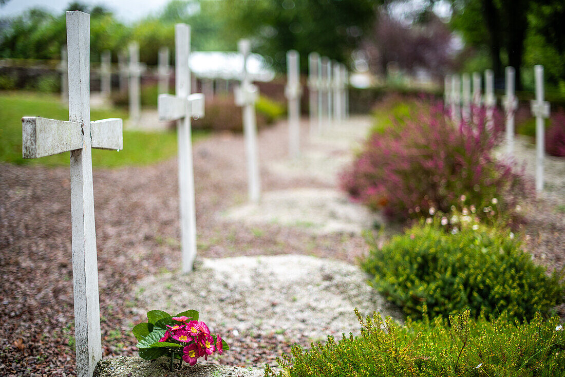 Row of white wooden crosses at the 16th century calvary site in Guehenno, Brittany, France, depicting a serene and solemn atmosphere.