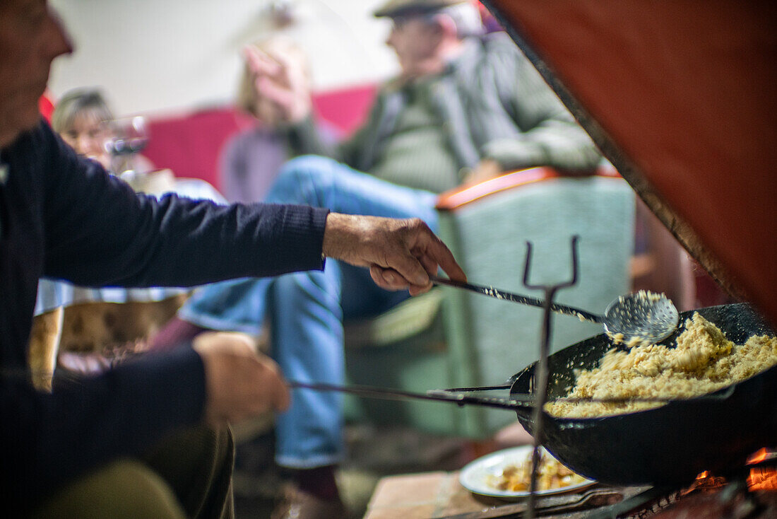 Kochen der traditionellen Migas Serranas in einer gemütlichen Umgebung in Villaviciosa de Córdoba, Andalusien, Spanien. Eine warme und einladende Atmosphäre mit Freunden und Familie.