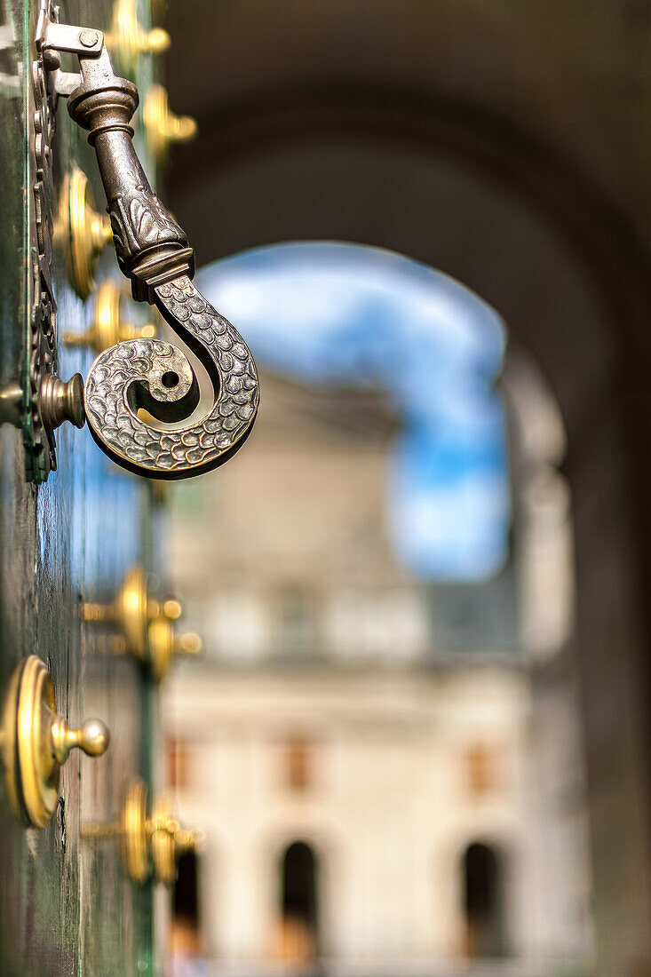 Nahaufnahme eines verzierten Türgriffs im Kloster San Lorenzo de El Escorial, mit Schwerpunkt auf den komplizierten Metallarbeiten.