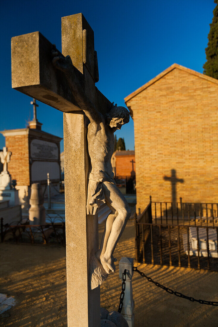 Detaillierte Kruzifix-Statue in der ruhigen Umgebung des Cementerio de San Fernando, Sevilla, Andalusien, die eine friedliche und besinnliche Atmosphäre einfängt.