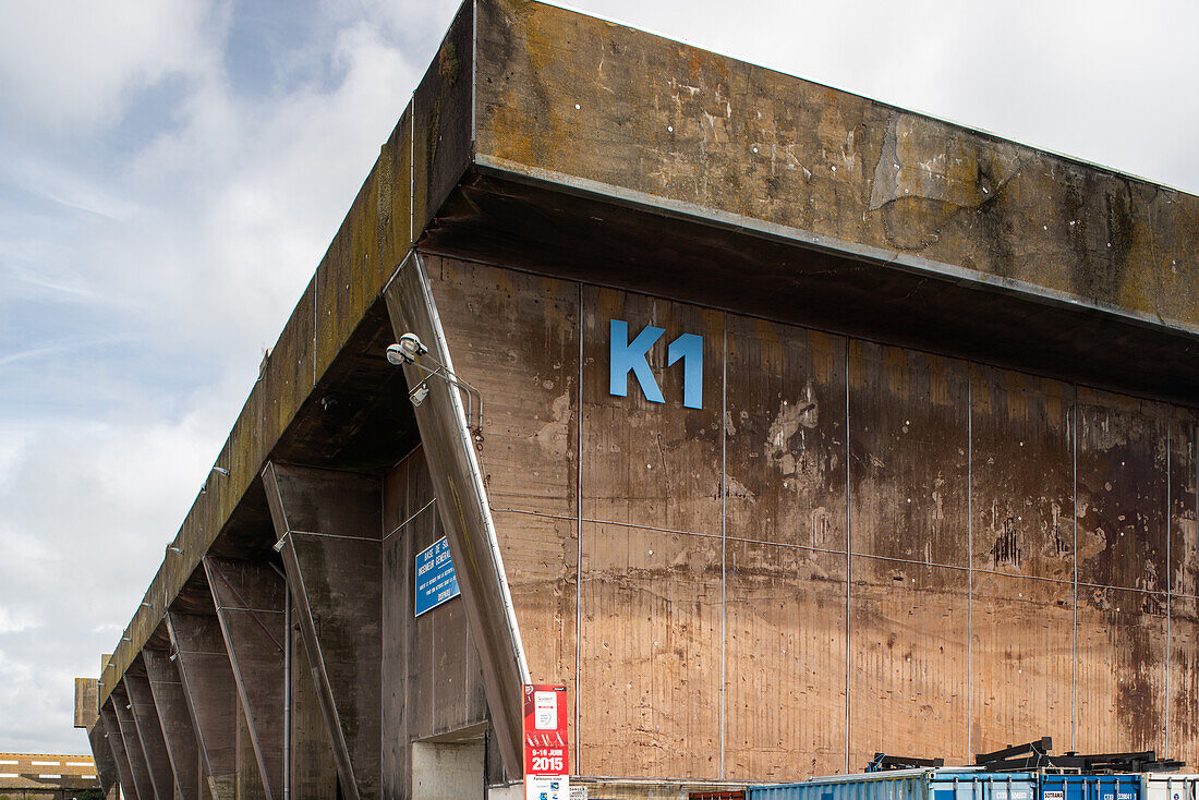 Außenansicht der historischen deutschen U-Boot-Basis aus dem Zweiten Weltkrieg in Lorient, Bretagne, Frankreich. Zeigt die massive Betonstruktur und die industrielle Umgebung.