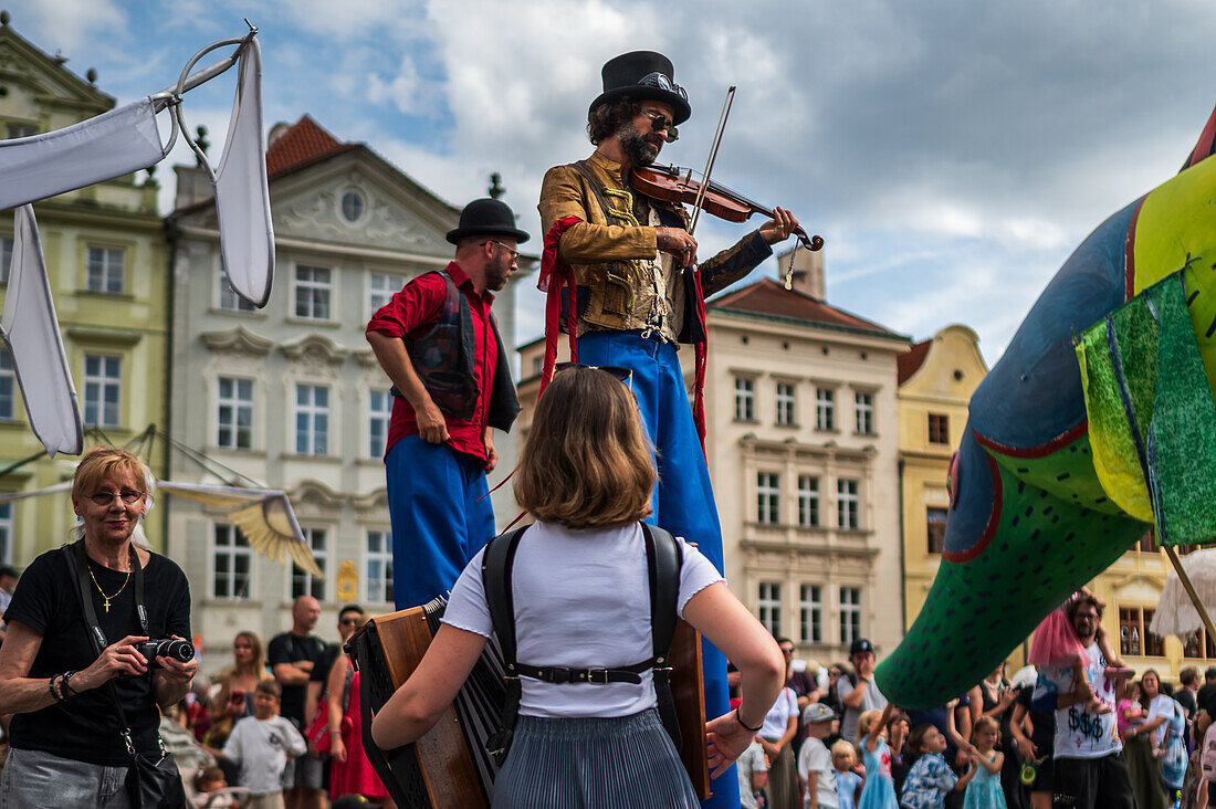 Artist plays violin while walking on stilts at the Parade of puppets from Marián Square to Old Town Square during the Prague Street Theatre Festival Behind the Door, Prague, Czech Republic