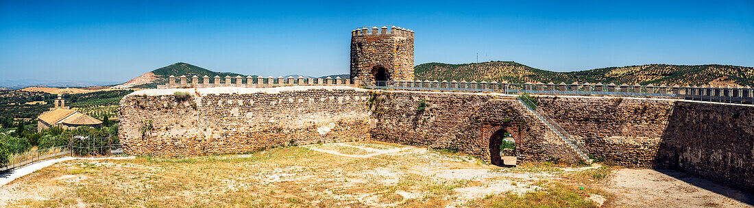 Panoramablick auf eine wunderschön restaurierte maurische Burg aus dem 14. Jahrhundert in Alanis de la Sierra, Sevilla, Spanien, mit malerischer Bergkulisse.