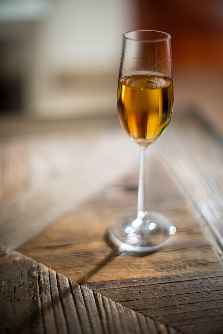 A glass of Palo Cortado sherry sits on a wooden table in Seville, Spain.