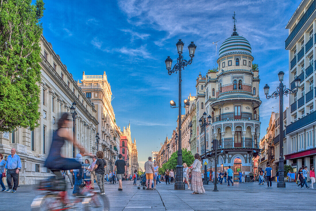 A bustling street scene on Avenida de la Constitucion in Seville, Spain, during a spring evening.