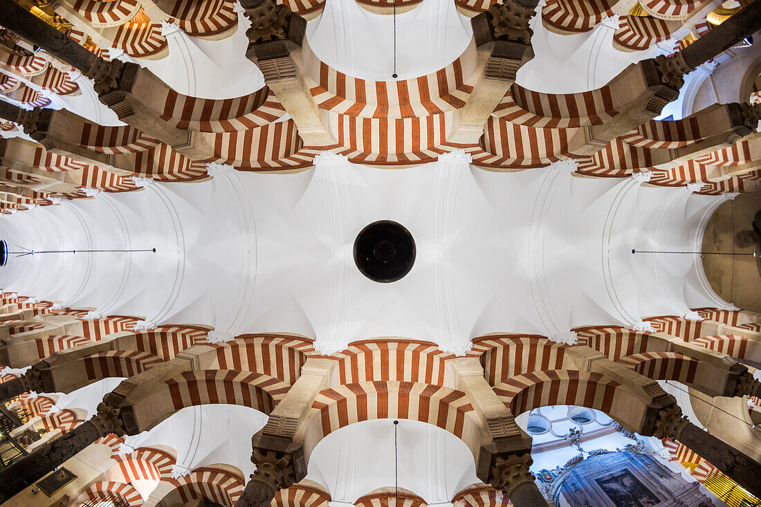 Fisheye view from below capturing intricate arches and ceiling inside the historic Cordoba Mosque located in Andalusia, Spain.