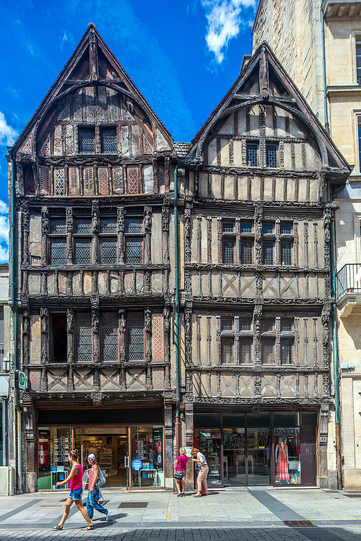 Blick auf historische Fachwerkhäuser in Caen, Normandie, Frankreich. Menschen, die bei klarem blauen Himmel an alter Architektur vorbeigehen.