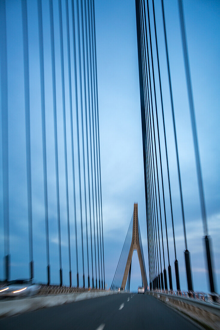 Blurred view of the Guadiana International Bridge connecting Spain and Portugal, captured from a moving car.