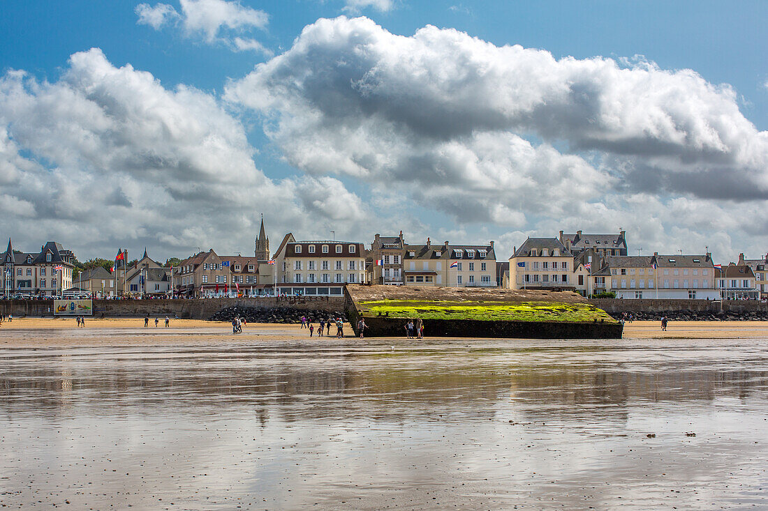 Panoramablick auf den Goldstrand in Arromanches, Normandie, Frankreich. Im Hintergrund sind die historischen Überreste von Mulberry B und reizvolle lokale Gebäude zu sehen.