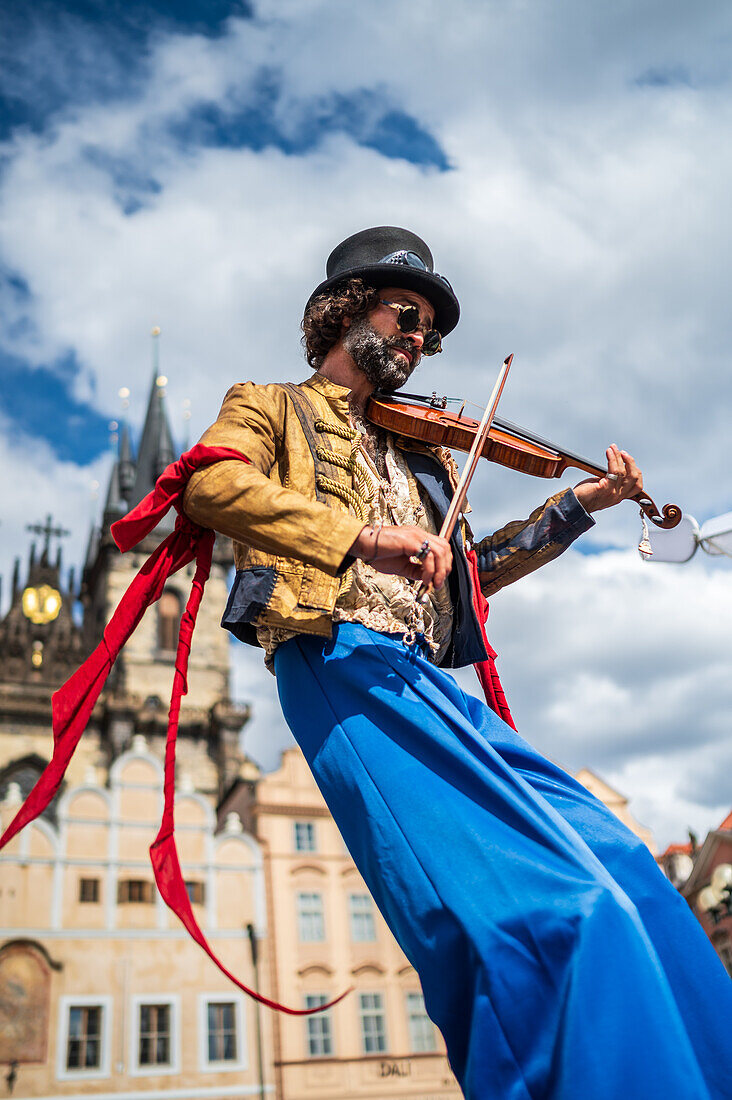 Artist plays violin while walking on stilts at the Parade of puppets from Marián Square to Old Town Square during the Prague Street Theatre Festival Behind the Door, Prague, Czech Republic