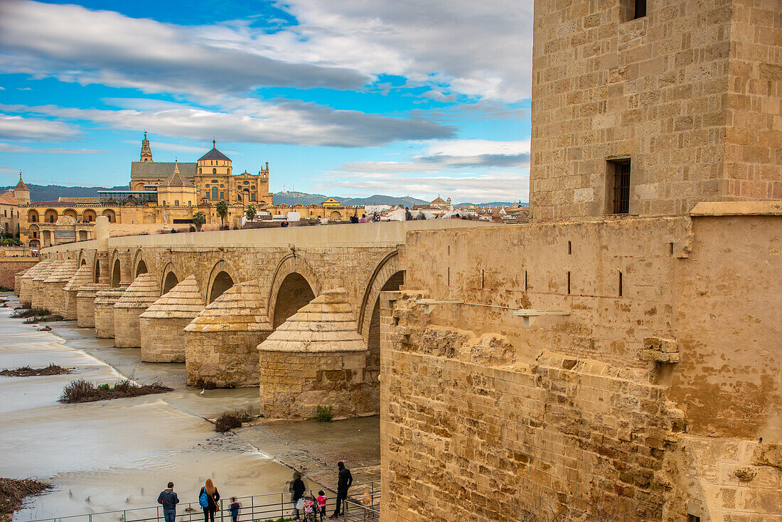 Blick auf die historische Puente Romano und die Kathedrale La Mezquita im Hintergrund in Cordoba, Andalusien, Spanien, an einem bewölkten Tag.