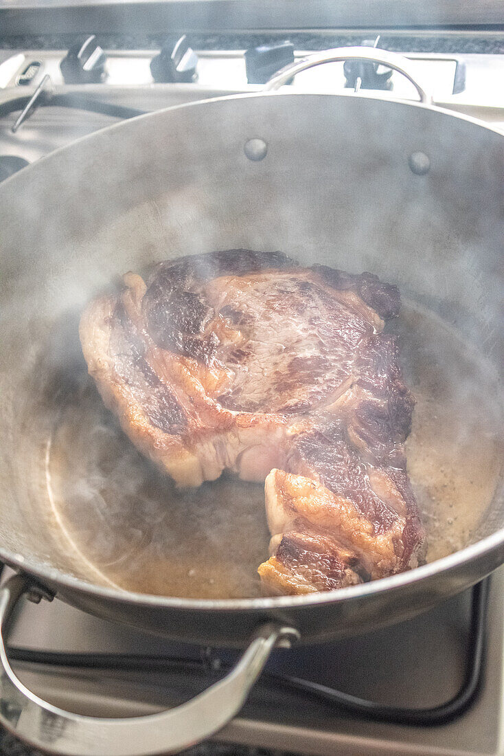 Ein dickes, abgelagertes Rindersteak brutzelt in einer Pfanne mit Rinderfett und sorgt für ein köstliches Bild in Sevilla, Spanien.