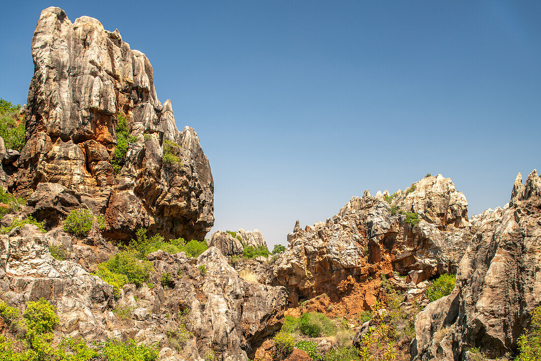 Majestätische Karstformationen im Naturdenkmal Cerro del Hierro in der Sierra Norte de Sevilla, Spanien, mit zerklüfteten Felsklippen und einem klaren blauen Himmel.